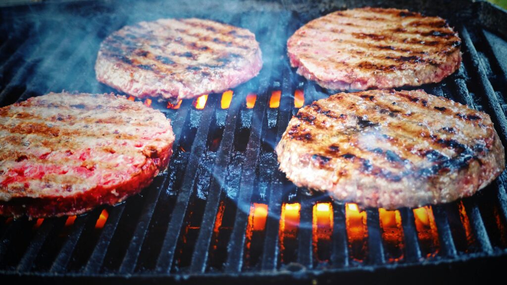 Juicy beef patties cooking on a hot grill, perfect for barbecue cookouts.
